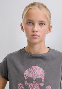 Grå bomulls-T-shirt med ett stort rosa och silverfärgat leopardtryckt dödskallemotiv. Rund halsringning med uppvikta korta ärmar.