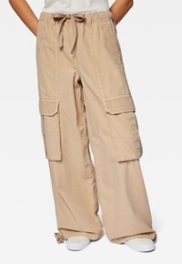 Beige Cargo-Hosen mit entspannter Passform, ausgestattet mit zwei großen Seitentaschen, einer Kordelzug-Taille und gerafften Säumen, aus leichtem Material gefertigt.