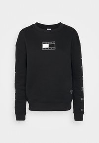 Svart sweatshirt i bomullsblandning, med en rektangulär vit logotyp på bröstet och "JEANS" tryckt vertikalt på båda ärmarna.