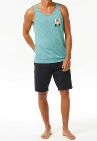 Débardeur turquoise avec un petit design graphique de poche, associé à un short noir. Tissu léger, coupe décontractée et style sans manches.