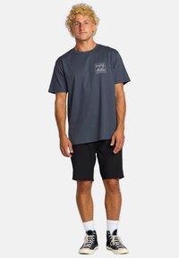 Navy blue cotton T-shirt with short sleeves, featuring a front graphic design. Paired with black shorts and black high-top sneakers.