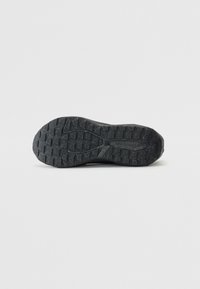 Sort gummisål med en struktureret, mønstrede slidbane med diamantformer, mærket 'new balance' på siden.