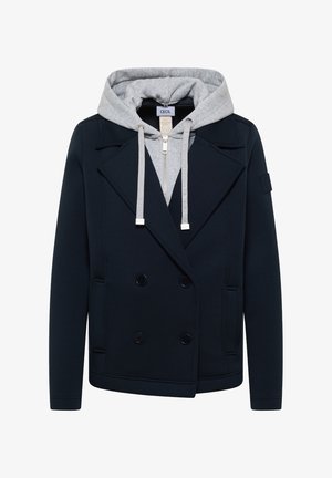 Veste noire à double boutonnage portée sur un sweat à capuche gris zippé avec cordons et capuche visibles, sans arrière-plan.