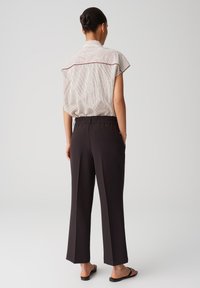 Women's back view featuring a striped short-sleeve blouse and high-waisted, dark pants with a wide leg and elastic waistband.