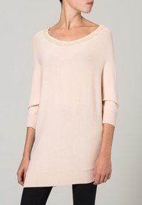 Maglione oversize rosa chiaro con scollatura a girocollo, tessuto a maglia testurizzata e polsini e orlo a costine. Presenta dettagli decorativi in perline.