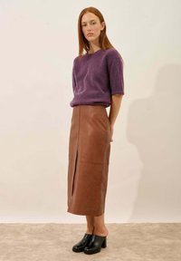 Fioletowy, dzianinowy top z krótkim rękawem, brązowa skórzana spódnica midi z rozcięciem z przodu i czarne obcasy z odkrytymi palcami. Gładka tekstura, dopasowany krój.