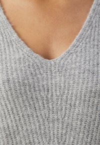 Szary dzianinowy sweter z głębokim dekoltem w kształcie V, prążkową teksturą i miękkim materiałem z widocznymi włókienkami, co zapewnia dodatkowe ciepło i komfort.