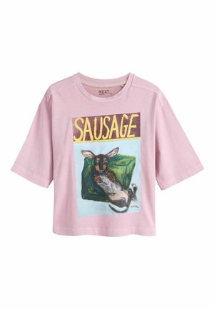 Light pink short-sleeve shirt with a graphic of a relaxed dog lying on a green cushion and the word "SAUSAGE" in large yellow letters above.