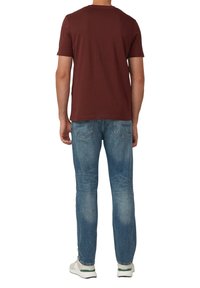 Bordowa bawełniana koszulka z krótkim rękawem, zestawiona z jasnoniebieskimi dżinsami. Całość uzupełniają neutralne kolorystycznie trampki.