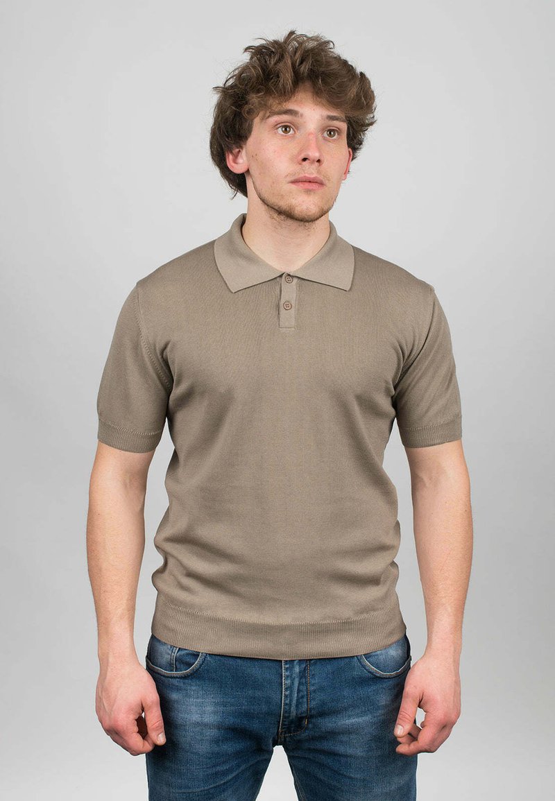 Beige polo tričko s krátkým rukávem, ribbovanou strukturou, skládacím límcem a třemi knoflíky. Spárováno s modrými džínami.