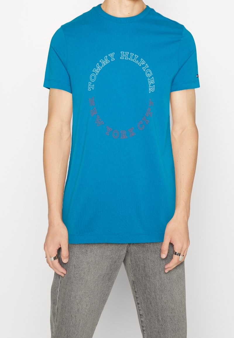 Blauwe katoen t-shirt met een ronde graphic met "TOMMY HILFIGER" en "NEW YORK CITY" in contrasterende kleuren. Korte mouwen en ronde hals.