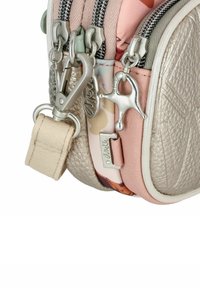 Bolso compacto con múltiples bolsillos que presenta texturas en dorado metálico y rosa suave, cierres de cremallera y detalles decorativos de hardware.