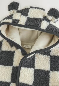 Harmaan ja kermaisen ruudullinen fleece-huppupeitto, jossa on korvaakkentteja, ribbitettu reuna ja pehmeä sisävuori; lappu näkyvissä sisällä.