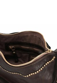 Braune Lederhandtasche mit Innenausstattung, einschließlich eines Reißverschlussfachs, goldenen Beschlägen und einer glatten Textur. Ausgekleidet mit dunkel gefärbtem Stoff und Nietenakzenten.