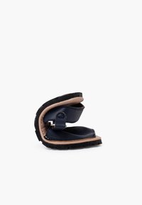 Vouwbare blauwe lederen sandaal met een zwarte rubberen zool, voorzien van een verstelbare band en een contrasterende beige binnenkant.