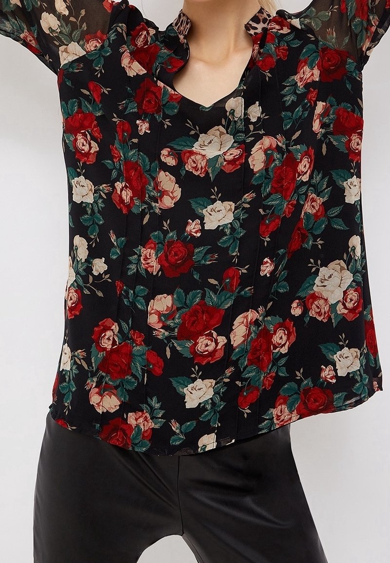 Blusa nera floreale caratterizzata da un design a motivi con rose rosse e crema, maniche trasparenti e scollatura con bottoni. Realizzata in tessuto leggero.