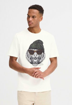 Hvid bomulds-t-shirt med et grafisk motiv af en tiger, der bærer solbriller og en grøn beanie. Kortærmet, med rund halsudskæring.