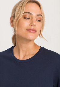 Námořnická modrá bavlněná tričko s krátkým rukávem a crew neck, hladký povrch a vyztužené švy na výstřihu.