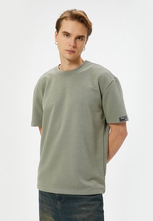 Lys grøn bomulds T-shirt med korte ærmer, rund halsudskæring og et lille mærke på venstre ærme. Blød tekstur, afslappet pasform.