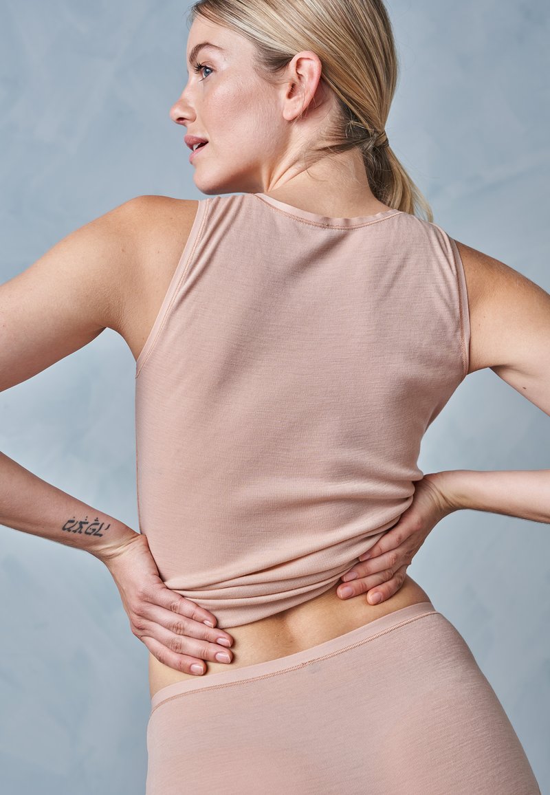 Nøgen tanktop og matchende underdele lavet af blødt, ribbet stof; har en rund halsudskæring og tætsiddende design, med minimale sømme og ingen synlige pynt.