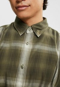 Green plaid shirt with a button-down collar, featuring a subtle check pattern and round buttons. Fabric appears lightweight with a smooth texture.