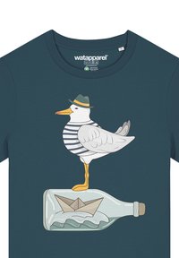 Ein marineblaues T-Shirt zeigt ein grafisches Motiv eines Möwe in einem gestreiften Hemd und Hut, die auf einer Flasche mit einem Papierboot darin steht.