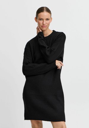 Schwarzes, geripptes Strickkleid mit langen Ärmeln und Rundhalsausschnitt. Der Stoff hat ein strukturiertes Muster und eine leicht lockere Passform.