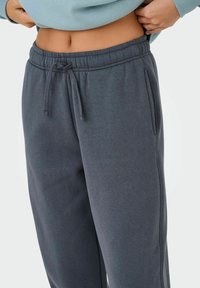 Pantaloni sportivi grigi in cotone con vita elastica, cordoncino regolabile e tasche laterali. Texture morbida e liscia con una vestibilità comoda.