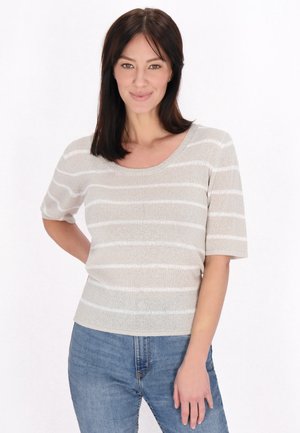 Beige strikket top med hvide vandrette striber, rund halsudskæring og korte ærmer, parret med blå denimjeans. Enkel, struktureret design.