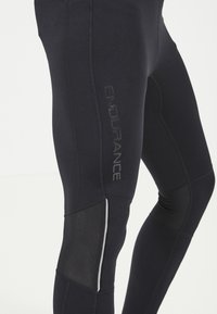 Schwarze Sportleggings mit strukturierten Einsätzen, enger Passform und reflektierenden Akzenten. Mit 'ENDURANCE'-Logo an der Seite.