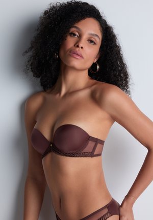 Soutien-gorge marron sans bretelles en tissu lisse, avec des accents en dentelle et un détail de fermoir doré. Présente une silhouette structurée et des panneaux latéraux transparents.