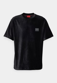 T-shirt noir en velours à manches courtes avec un col rond et un petit patch logo « HUGO » sur la poitrine gauche.