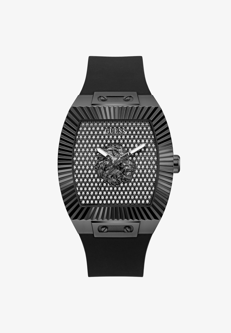 Montre Guess noire avec cadran carré orné de strass, emblème de tête de lion, aiguilles argentées et bracelet en silicone noir.