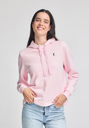 Sudadera rosa claro con capucha, que presenta un pequeño logotipo negro en el pecho. Hecha de una tela suave, con cordones y puños acanalados.