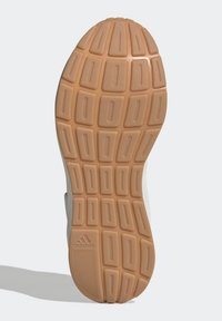 Semelle en caoutchouc marron avec un motif en grille et des rectangles en relief. Présente des accents texturés ; le côté gauche comprend un logo en relief.