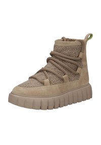 Beežid ülepaaresne sneakerid, millel on tekstuuriga pealmine osa koos fliisist aktsentidega, ümar varvas, paks tald ja köisnöörid. Roheline tõmblukk taga.