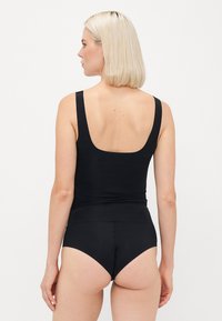Black bodysuit with wide shoulder straps, scoop back, and seamless texture. Paired with high-waisted black briefs, simple design.