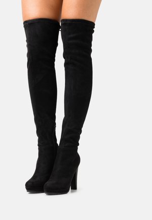 Schwarze Wildleder-Stiefel über dem Knie mit hohem Blockabsatz, runder Zehenform und seitlichem Reißverschlussdetail. Glatte Textur mit einer figurbetonten Silhouette.