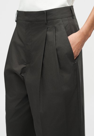 Σκούρο γκρι παντελόνι με πιέτες, πλαϊνές τσέπες και λεία υφή, ραμμένο για εφαρμοστή σιλουέτα.