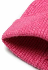 Bonnet en tricot rose avec une texture côtelée, revers replié et tissu doux, mettant en avant une couleur vive adaptée à l'hiver.