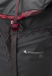 Grijze waterdichte jas met rode accenten, voorzien van een gestructureerde voering, verstelbare banden en een uniek gegolfd naaddetail.