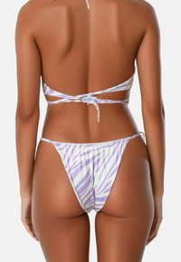 Paars en witte zebra print bikini met dunne bandjes en minimale bedekking, voorzien van een textuurstof en verstelbare schouderbandjes voor een veilige pasvorm.