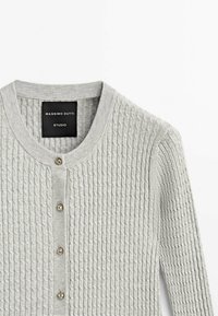 Harmaa neulecardigan, jossa on teksturoitu kuvio, pyöreä pääntie ja kolme metallista nappia edessä. Massimo Dutti -logo näkyvissä.