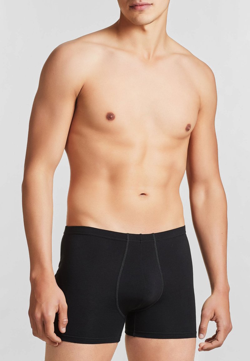 Boxer shorts neri in cotone con una vestibilità aderente, caratterizzati da una superficie liscia e cuciture a contrasto lungo la vita e le gambe.