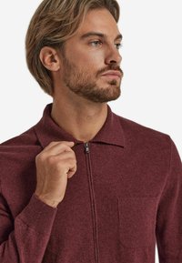 Burgundowa bluza zapinana na zamek z kołnierzem, teksturowany materiał, kieszonka na piersi, z prążkowanymi mankietami i eleganckim, dopasowanym krojem.
