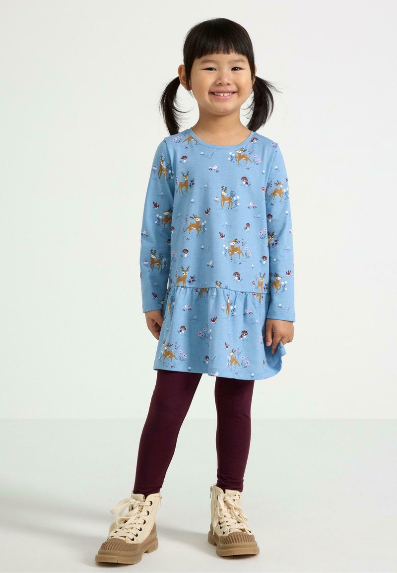 Blå langærmet kjole med blomstermønster og hjortetryk, lagdelt kant, parret med burgunder leggings og brune snørebåndsstøvler. Glat stoftekstur.