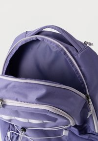 Μωβ σακίδιο πλάτης με ανοιχτό κύριο διαμέρισμα, μπροστινή τσέπη με φερμουάρ, επενδεδυμένη λαβή και ρυθμιζόμενο κορδόνι bungee σε πλέγμα στην πλαϊνή τσέπη.