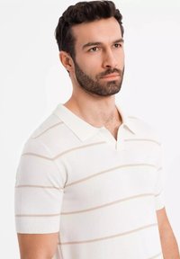 Lyhythihainen polo-paita, neulottua kangasta, valkoinen vaaleanpunaisilla vaakaraidoilla, jossa on tasainen kaulus ja ribattu hihansuut.