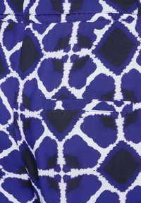 Tessuto blu e bianco a motivo geometrici, con un sottile dettaglio per tasca integrato nella trama del motivo.
