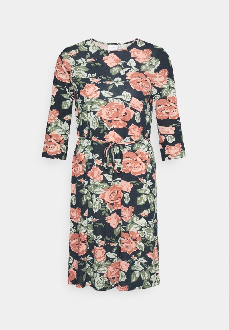Vestido floral com mangas compridas, decote redondo e cinto atado. Fundo escuro com rosas cor-de-rosa e folhas verdes. Textura de tecido suave.